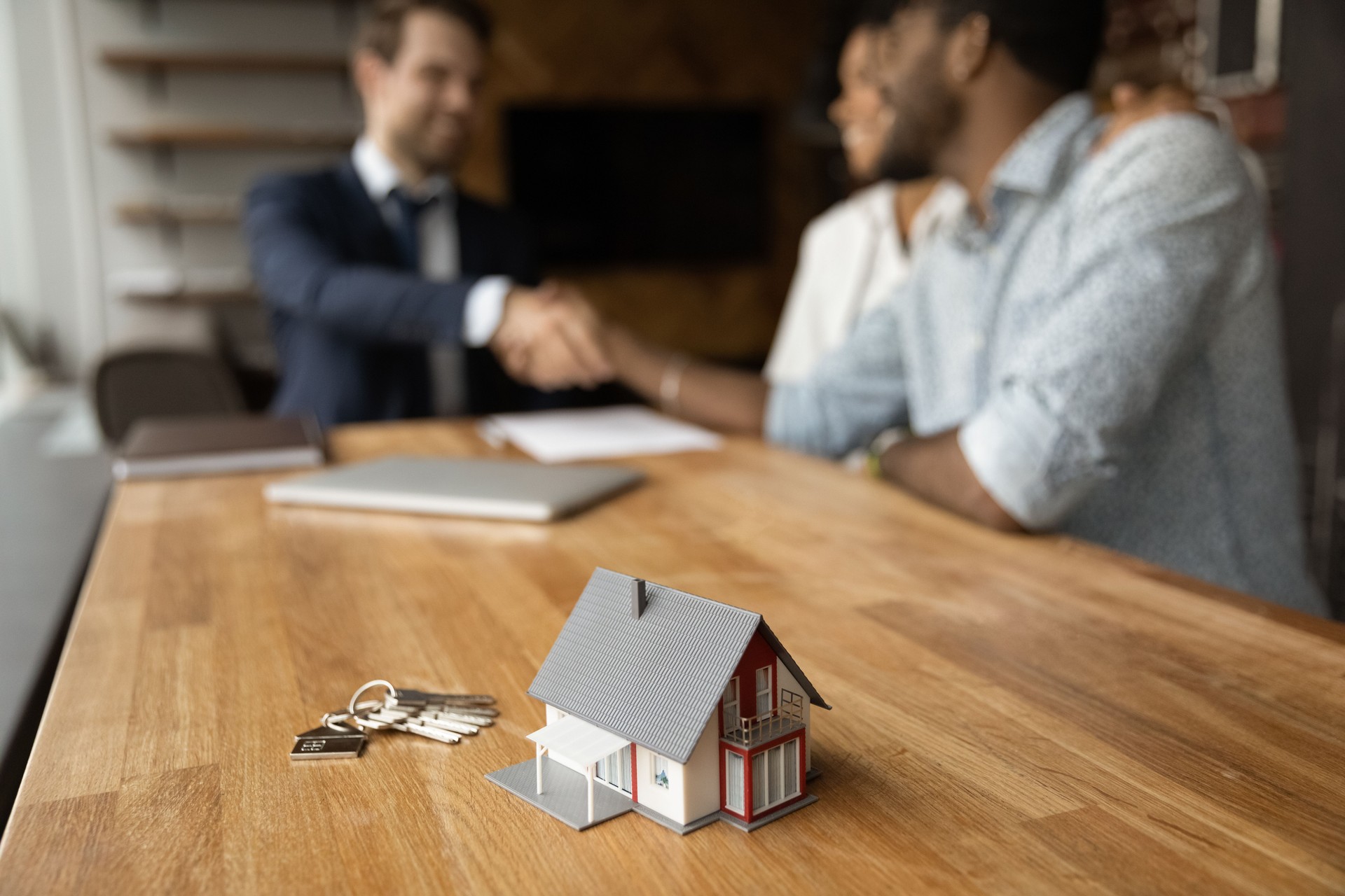 Closeup of keys and toy cottage house on wooden table